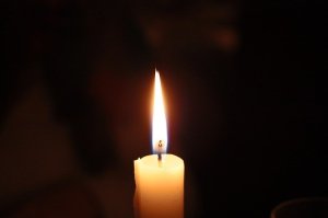 Brennende Kerze vor schwarzem Hintergrund 